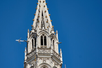 A plane passing by the Brussels City Hall Tower on the Grand Place