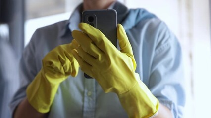 smartphone in hands of worker in yellow gloves, using phone or app to call, close-up video