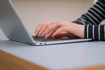 ノートパソコンで仕事をする女性の手元のクローズアップ
