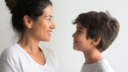 40 year old Latin mother standing to the side looking and smiling at her 7 year old Latin boy son, optimistic faces, in a large space with white background, optimistic faces, photo style