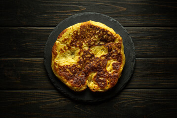 Round fried homemade pancake on black dessert sorting board. Delicious snack serving concept