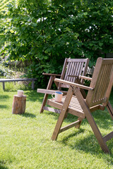 Two wooden chairs in a cozy garden. The concept of a summer vacation in nature.