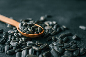 sunflower seeds on a wooden spoon, black background