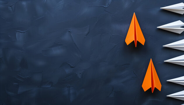 Two orange paper planes stand out from a line of white paper planes on a textured dark background, symbolizing leadership and innovation.
