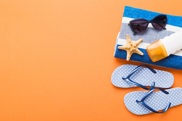 Summer holiday concept. Top view of beach towel, flip flop and sunscreen cream on table Top view...