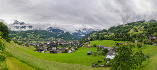 Obraz premium panorama from village Schruns in Montafon, Vorarlberg, with small alpine houses between forested steep slopes and flowered meadows. in the mountains from Rhätikon, at the border to Switzerland, cloudy