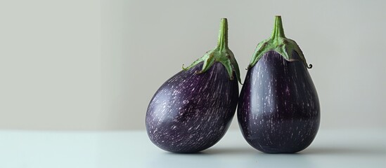 The green stems of the eggplants stand tall and proud, adding a touch of natural beauty to the scene against the stark white backdrop