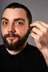 Obraz premium Beard care. Closeup of male face and pipette with a oil for a beard growth