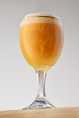 Goblet filled with golden, hazy beer topped with thick, creamy foam against grey studio background. Concept of food and drink, celebration, Oktoberfest, beverage industry. Ad