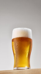 Image of cold, golden, lager alcohol drink, beer with thick white foam against grey studio background. Concept of food and drink, celebration, Oktoberfest, beverage industry. Ad
