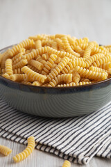 Raw Dry Organic Italian Fusilli Corti Bucati in a Bowl, side view.