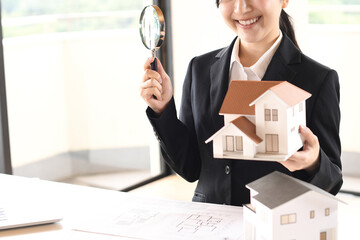 虫眼鏡で住宅模型を除くスーツ姿の若い女性