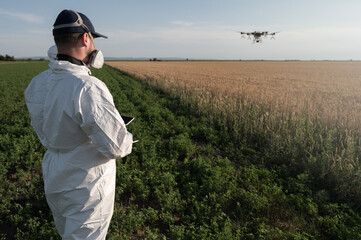 Man operates agricultural drone. Modern technologies in agriculture. Industrial drone flies over a green field and sprays pesticides to increase productivity and destroys harmful insects. Technologies