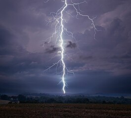 Dramatic lightning bolt striking down during a thunderstorm over a rural landscape. Lewisburg