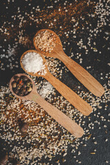 Wooden spoons with different spices on a black background, banner