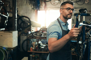 Man, bicycle technician and fix with inspection for maintenance or small business at repair shop. Young male person, cycling mechanic or engineer working on bike with tools or equipment at workshop