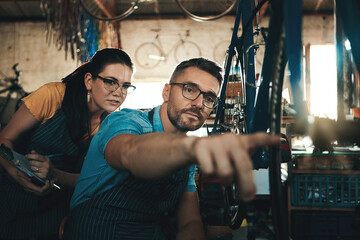 Bicycle technician, working and repair in shop with chains, frame and tools for maintenance or cycling. Man, bike and mechanic in workshop as teamwork for gear, inspection and safety with glasses