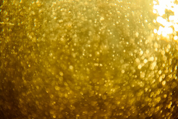 Abstract blurred golden glitter texture with sparkling bokeh lights creating a festive and...