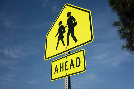 School crossing ahead signage against a blue sky background.