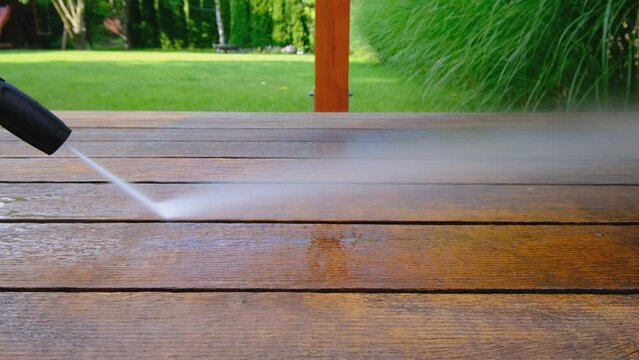 cleaning terrace with a power washer - high water pressure cleaner on wooden terrace surface - 4K video