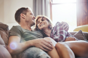 Happy, couple and hug on sofa with laughing at home for funny joke, humor and romance in relationship. Peace, man and woman with smile in living room for joy, comfort and bonding together on weekend