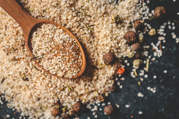 Wooden spoon with sea salt and spices on black background