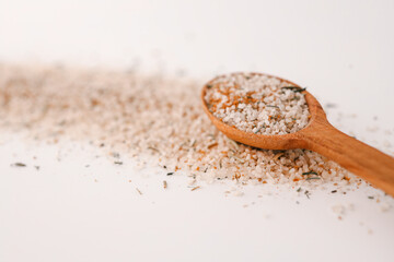 Italian salt with spices in a wooden spoon on a white background