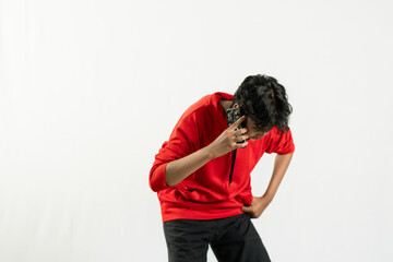 Young Indonesian man in red shirt looks very angry as he is on a voice call, concept of Indonesia's independence day August 17, isolated white background.   