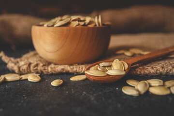 pumpkin seeds in a wooden bowl and vintage scoop. Close up on a black background. copy space for text