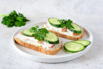 a plate with a sandwich on it and a slice of cucumber 