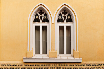 Elegant double gothic windows set against a vibrant yellow wall, showcasing classic architectural details.
