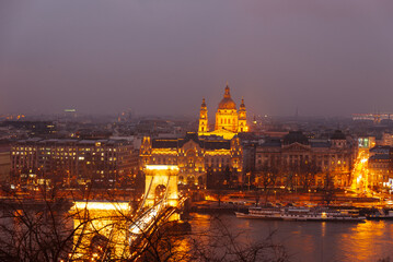 Enjoy the nighttime panoramic view of Budapest showcasing illuminated landmarks and their reflections on the water