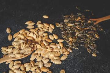 Scattering pumpkin seeds in a wooden spoon on a black background
