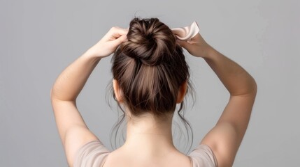 Fototapeta premium Woman with a smooth bun hairstyle from the back. on gray background