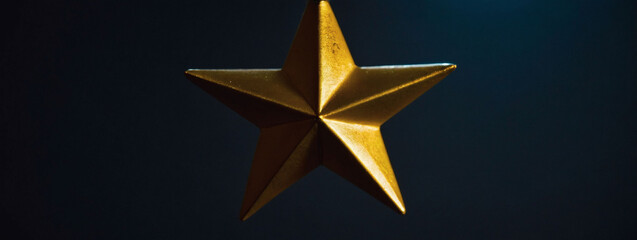 Hanging gold star shines in dark.