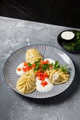 Traditional Uzbek Manty with Sour Cream and Paprika Garnish on a Decorative Plate