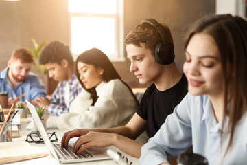 In the library, a diverse set of students focuses on their screens, deeply engrossed in research. The mood is quiet yet energetic, fostering a spirit of shared learning.