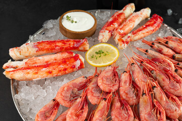 Enjoy a lavish Fresh Seafood Platter with Shrimp, Crab Legs, and Dipping Sauce, all on ice. Close up