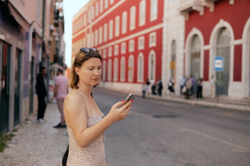 City travel concept. Tourist Woman looking at a ticket on her phone and waiting for transport at...