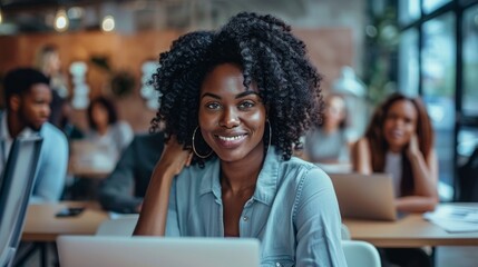 She is surrounded by other people, some of whom are also using laptops