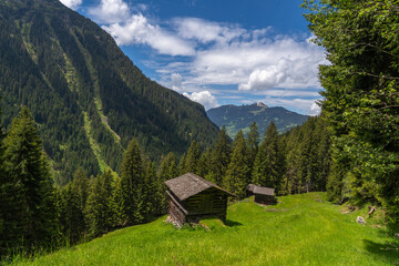 alpine houses on the edge of forest, wooden cabin next to the path, on the raodside, while hiking, we come across old alpine three stage farming huts, hiking in the mountains from Vorarlberg