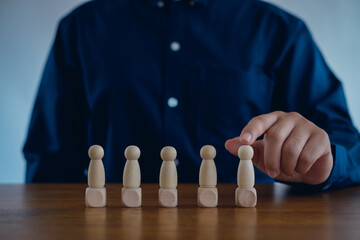  Human Resource Management or Staff Recruitment Concept of leading business. choice of an employee leader from the crowd. businessman holds an employee in his hand. wood block people.