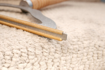 Carpet rake blade close up. Carpet brush or comb on carpet stairs. Pet hair remover with wooden handle. Cleaning gadget used to remove hair and lint from fabrics, carpet or furniture. Selective focus.