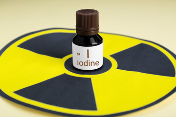 Bottle of medical iodine and radiation sign on beige background