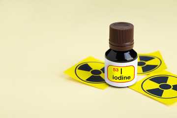 Bottle of medical iodine and radiation signs on beige background. Space for text