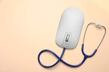 Computer mouse with stethoscope on beige background, top view. Online medicine