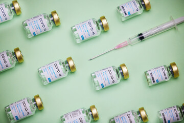 Health, syringe and glass bottle of vaccine by green background, treatment and illness prevention. Medical, insulin and injection for disease, coronavirus and diabetes for immune wellness in studio