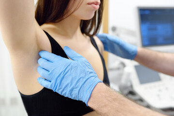 Doctor mammologist examines woman breasts and lymph nodes. Correcting the shape of the breast -...