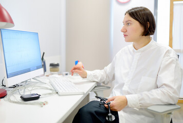 A cardiologist during appointment of patient. Doctor shows EKG on the screen of computer and explains about deviations of heart work. Cardiology consultation and treatment