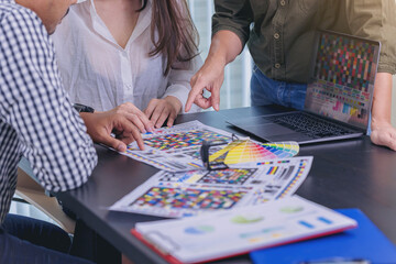 Worker checking print quality of media graphics proof print and color tone in printing industry. Selected focus